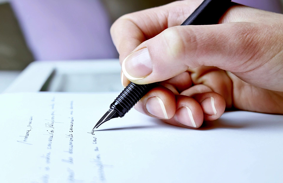 A person writing on paper with a pen.